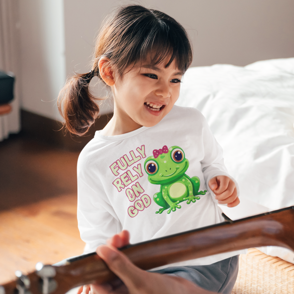 FROG. Fully Rely On God. This cute little girl toddler long sleeve t-shirt has an adorable green frog wearing a pink bow. Alongside are the words Fully Rely On God in light green and pink. Perfect for your toddler girl!