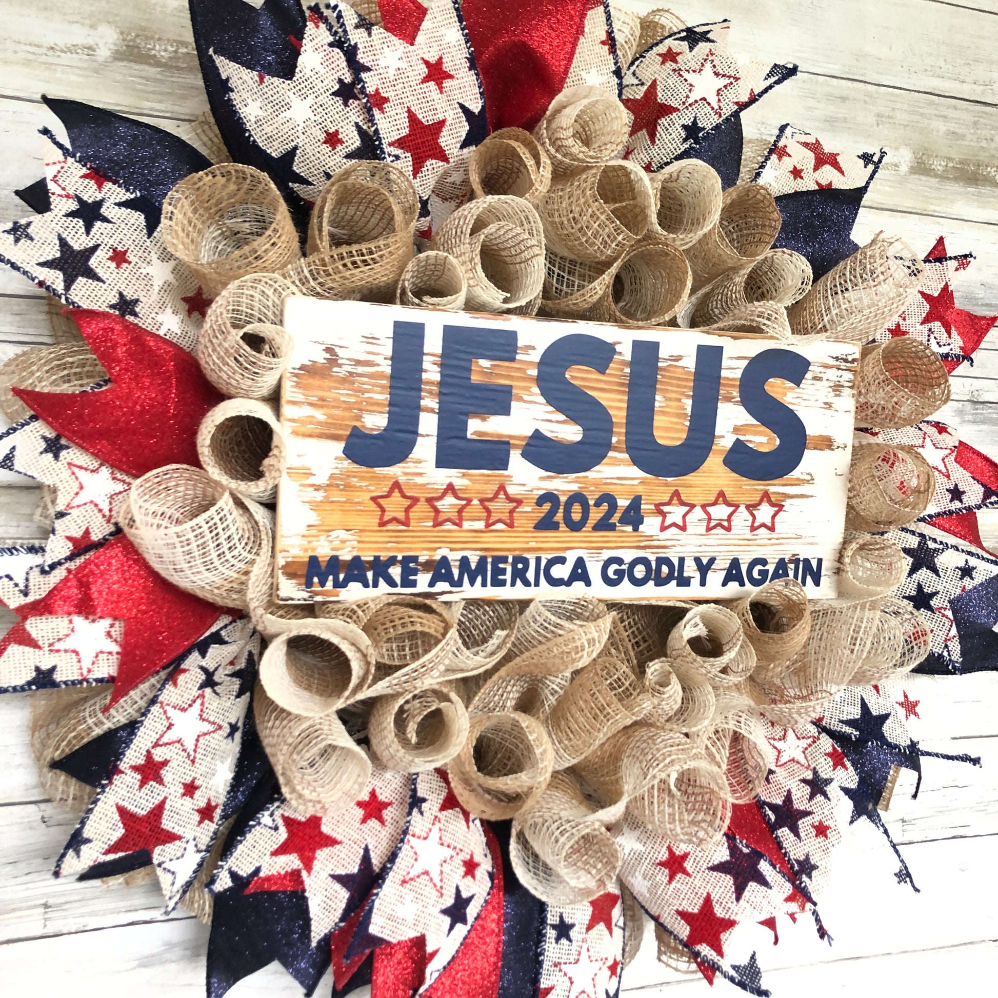 Celebrate your faith and patriotism with this handmade door wreath featuring the message "Jesus 2024 Make America Godly Again." The vibrant blue and red glitter ribbon add a festive touch. Show your support for a godly America in the upcoming election.