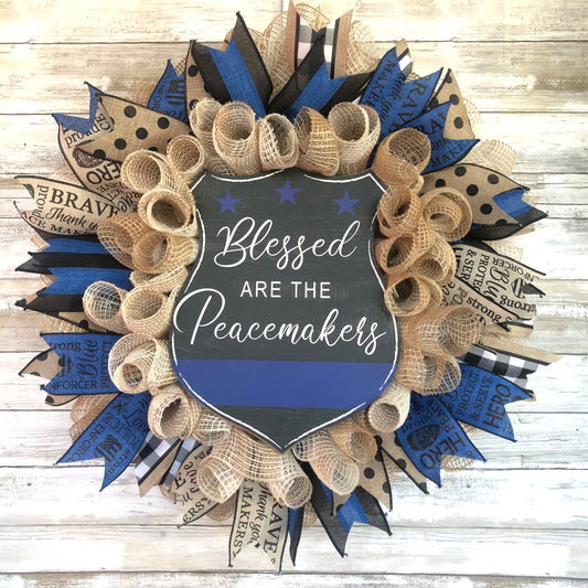 Blessed Are The Peacemakers! This beautiful beige. black and blue wreath displays your homes support for the police that put their lives on the line to serve and protect our communities. Show your support with this thin blue line wreath featuring a black badge shaped sign and the words Blessed Are The Peacemakers. Cataldo Creations Handmade Door Wreaths